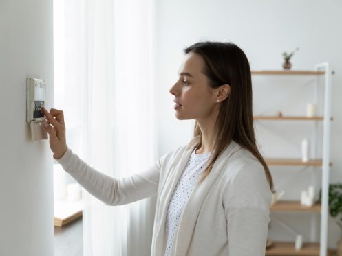 Woman adjusting her thermostat in her home