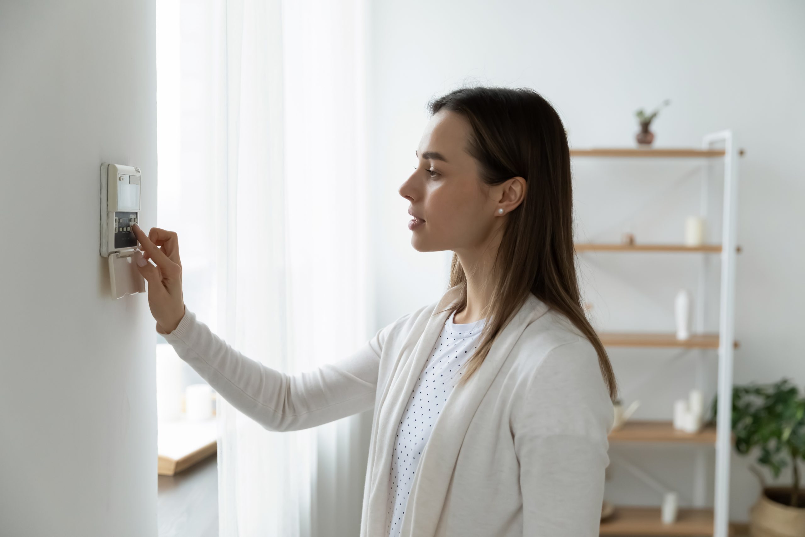 Woman adjusting her thermostat in her home