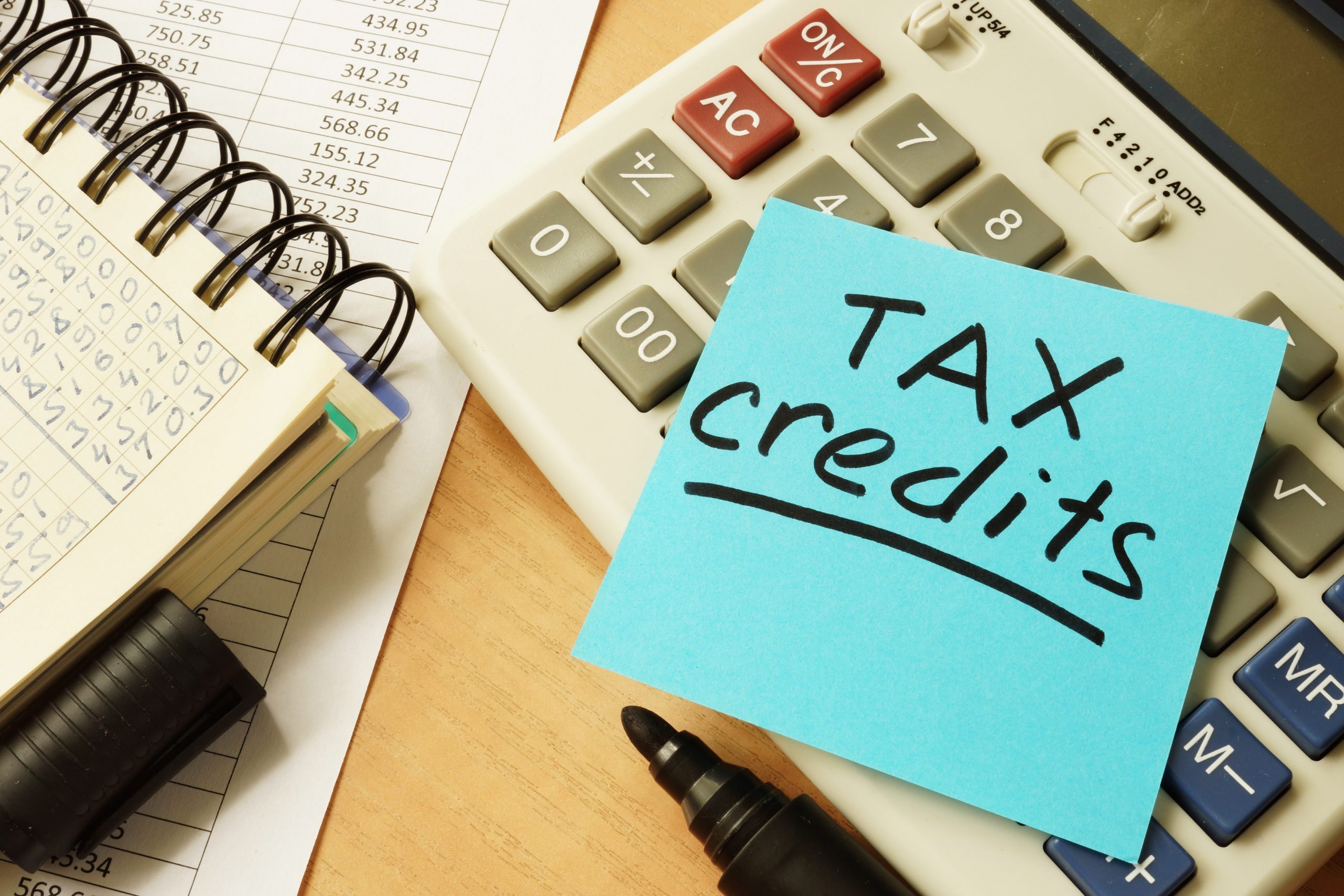 Notepad, calculator and note reading 'tax credits' depicting federal tax credits