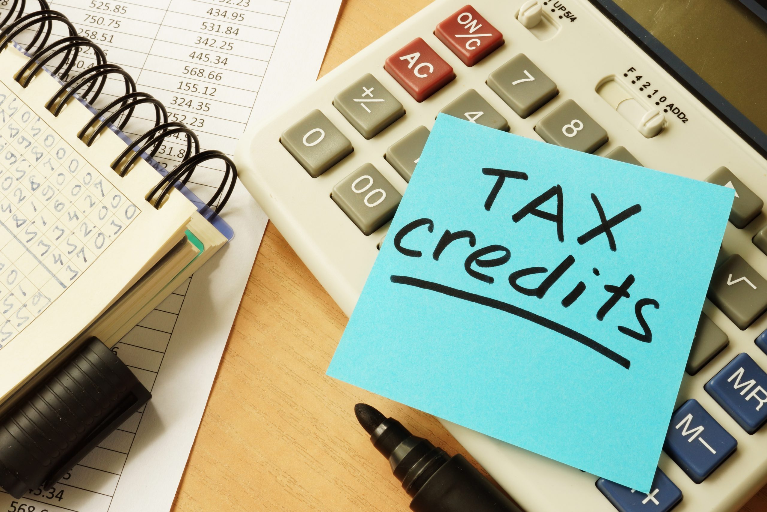 Notepad, calculator and note reading 'tax credits' depicting federal tax credits