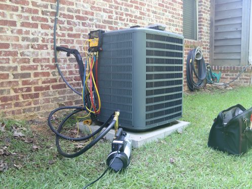 AC/heating unit being inspected for seasonal HVAC maintenance