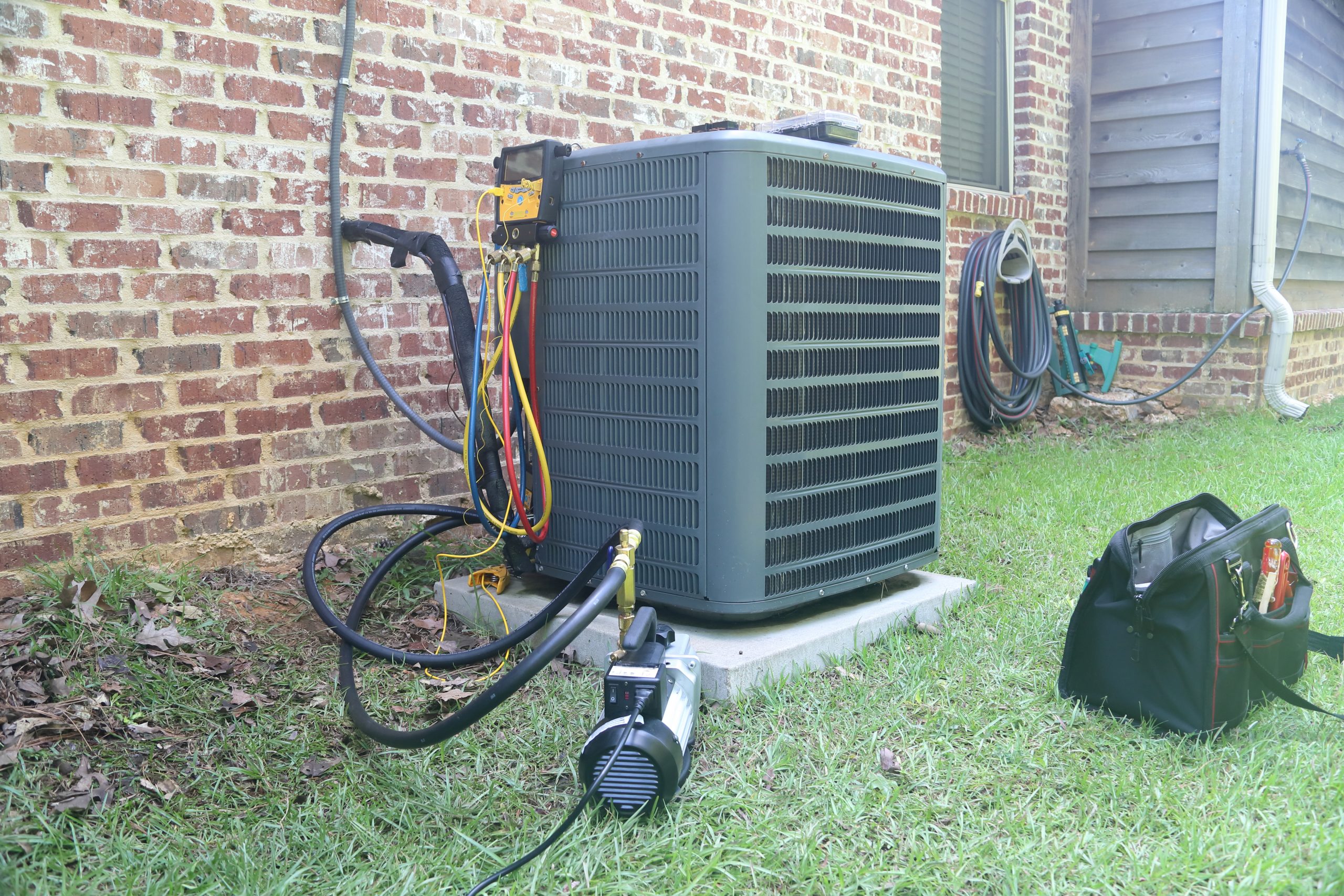 AC/heating unit being inspected for seasonal HVAC maintenance